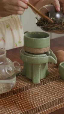 Anonim bir kadının ev kahvaltısı sırasında teaware kullanarak bitki çayı yaptığı dikey bir fotoğraf.