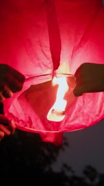 Ulusal bayram kutlamaları sırasında gökyüzü fenerlerini fırlatan isimsiz insanların dikey görüntüleri.