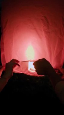 Gece ulusal bayram kutlamaları sırasında insanların gökyüzüne kırmızı fener saldığı dikey çekim.