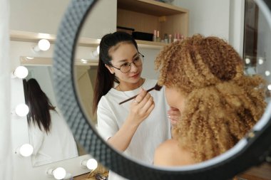 Profesyonel stilist kozmetik uyguluyor ve çekim için model hazırlıyor