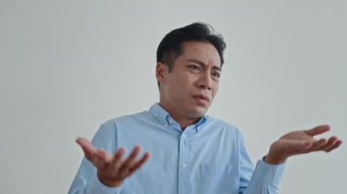 Orta boy Asyalı asyalı bir adam, beyaz arka planda vücut dili izole edilmiş bir şekilde bilmiyorum diyor.