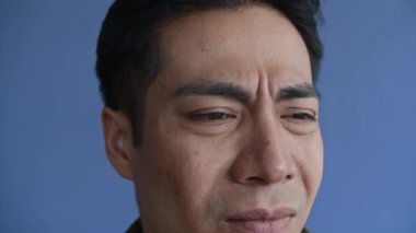 Kuşkulu Asyalı milenyum kuşkusu yüzünden sorunlarını mavi arka planda izole etmek.