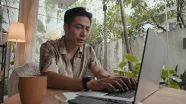 Orta boy Asyalı esneme erkek serbest çalışan kablosuz bilgisayarı bitirirken merkez ofiste otururken.
