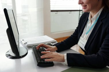 Businesswoman typing on keyboard and working online while sitting at her workplace in office clipart