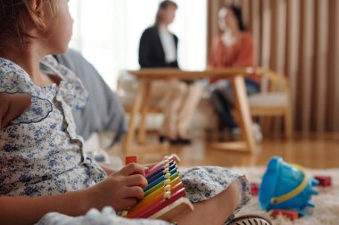 Sosyal hizmetler görevlisi evde annesiyle konuşurken evlat edinilmiş çocuk oyuncak oynuyor.