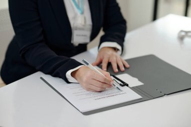 Close-up of social worker filling document at table in office clipart