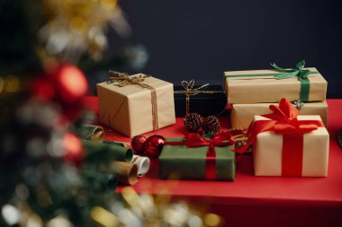 Several beautifully wrapped presents arraigned on red surface with festive decorations, representing joyous holiday spirit. Boxes adorned with ribbons and bows for celebration clipart