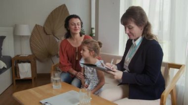 İhtiyacı olan anne ve kızını ziyaret ederken orta boy beyaz kadın sosyal hizmet görevlisi kartı doldurma.