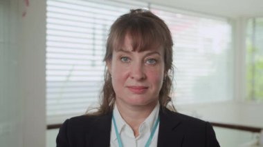 Kameraya gülümseyen Kafkas kökenli kendine güvenen kadın ofis çalışanının orta boy yakın portresi.