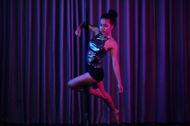 Yetenekli bayan dansçı zarif bir şekilde direk dansı yapıyor. Şık ve esnek sahne arkası hareketlerine karşı dayanıklılık ve esneklik gösteriyor.