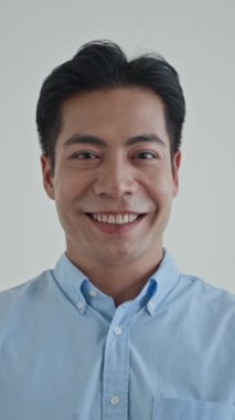 Asyalı etnik kökenli bir gencin dikey portresi beyaz kameraya öpücük yolluyor.