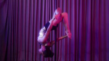 Neon Stüdyoda genç Asyalı bir kadının baş aşağı dans direğine asıldığı uzun bir çekim.
