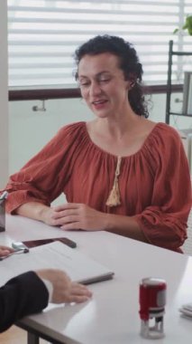 Ofiste masada oturan beyaz bir kadına danışmanlık yaparken dikey çekim.