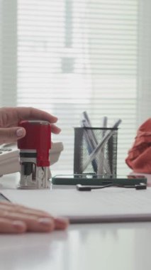 Tanımlanamayan yöneticinin ofisindeki masada müşterinin belgelerini damgalayan dikey resimleri.