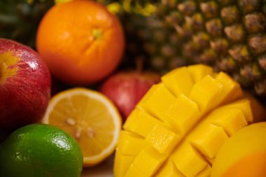 Mango, ananas, limon, portakal ve elmalardan oluşan canlı tropikal meyve çeşitleri zengin dokularını ve canlı renklerini dinamik bir kompozisyonda sergiliyor.