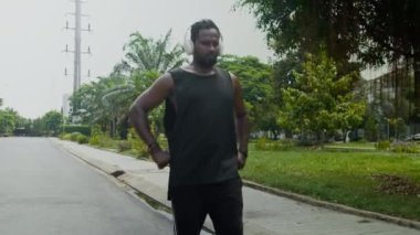 Yerel parkta yürürken kablosuz kulaklıklı profesyonel erkek dansçının orta uzunluktaki görüntüsü.