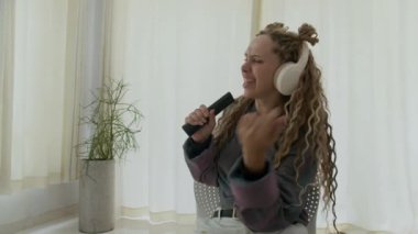 Kablosuz kulaklıkla müzik dinlerken ve evde dans ederken beyaz kadının görüntüsünü büyüt.