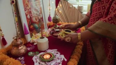 Geleneksel Hint kıyafetleri içinde üç kişilik ailenin Diwali 'deki sunakta puja yapmak için toplandığı el kamerasıyla çekilmiş bir fotoğraf.
