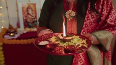 Diwali kutlamaları sırasında sari tepsisi içinde elinde yanan parayla isimsiz bir kadının görüntüsü.
