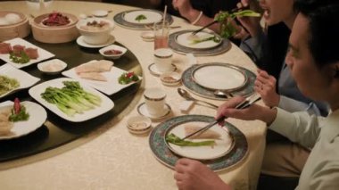 Son moda Asya restoranında aile üyelerinin çeşitli yemekler yediği görüntüler.