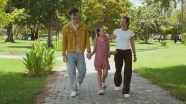 Kızların ve ebeveynlerin yaz parkında yürürken yavaş çekimleri.