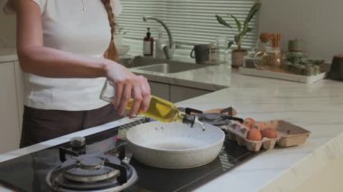 Tanımlanamayan bir kadının kahvaltıda ev mutfağında yumurta pişirirken görüntüsü.