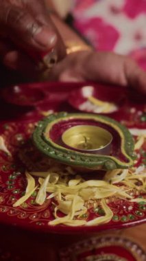 Diwali kutlamaları sırasında tabakta diya yakan insanların dikey çekimleri