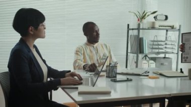 Tekerlekli sandalyedeki beyaz erkek işadamının toplantı sırasında elinde mali kağıtlar tutarken çeşitli meslektaşlarıyla iletişim kurarken görüntüsü.