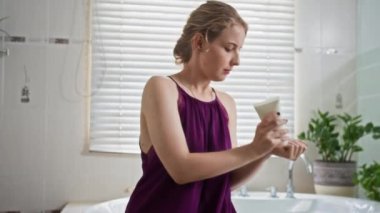 Z jenerasyonunun düşük açılı görüntüsü beyaz kızın vücut derisine losyon sürmesi banyoda günlük rutinin bir parçası.