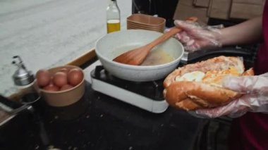 Anonim fast food karavanı işçisinin dışardaki malzemelerle ekmeği doldururken çekilen görüntüsü.
