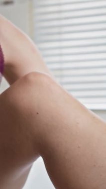 Kafkas Gen Z kadınının sabah rutini olarak bacakları ovalarken dikey pozu.