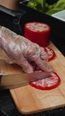 Kafede yemek pişirirken jambon dilimleyen isimsiz birinin dikey resmi.