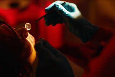 Muayene sırasında özel diş aletleri kullanan dişçi, muayene sürecinin yakın çekiminde gösterilen hassasiyet ve diş bakımına odaklanır.