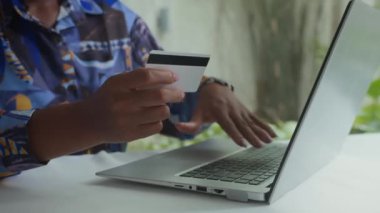Evdeki dizüstü bilgisayarla online ödeme yaparken banka kartı bilgilerini yazan tanınmayan bir kadının yakın plan görüntüsü
