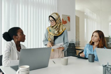 Modern ofiste üç iş kadını birlikte proje üzerinde çalışırken tartışıyorlar. Toplantı sırasında dizüstü bilgisayar ve tablet kullanmak