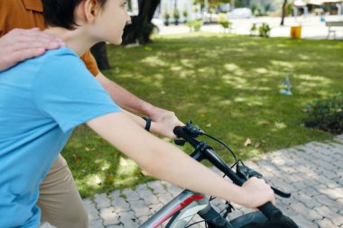 Çocuk dışarıda büyükbabasıyla bisiklete biniyor.