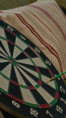 Kanepede çizgili konfeksiyon ile rahat bir dairede oynarken tekneye dart atan tanınmayan oyuncuların dikey yakın çekimi.