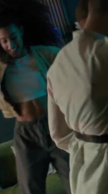 Çok ırklı arkadaş grubunun dikey görüntüsü. Kahkahalar ve ev ortamının rahatlığı içinde dans ediyorlar. Işıldayan ışıklar ve rahatlatıcı titreşimlerle dolular.