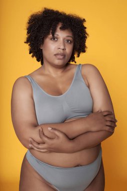 Sarı arka planda iç çamaşırlı Afro-Amerikan kızın portresi.