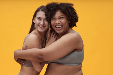 Birbirlerini kucaklayan ve kameraya gülümseyen mutlu kızların portresi.