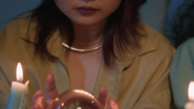 Gece arkadaşlarıyla fal bakarken genç Asyalı kızın kristal küreyi tahmin edişinin el kamerası görüntüsü.