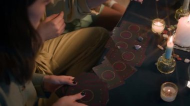 Yüksek açılı, tanınmayan kızların sarkacını kullanırken tarot kartları ve mumlarla tahmin oturumları yaparken.