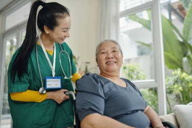 Evde engelli yaşlı bir kadını önemseyen genç bir sosyal hizmet görevlisi.