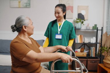 Bakıcı evde ona bakarken kıdemli bir kadın Walker 'la yürümeye çalışıyor.