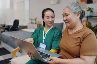 Sosyal hizmet görevlisinin yardımıyla bilgisayar kullanmayı öğrenen kıdemli bir kadın.