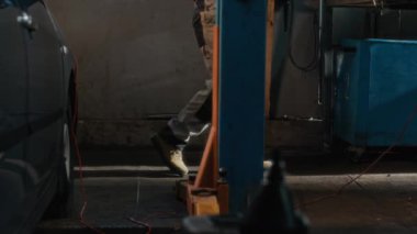 Araba servisi merkezinde çalışan tanınmayan, üniformalı bir erkek tamircinin düşük görünümü