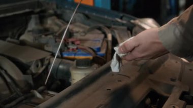 Tanımlanamayan otomobil tamircisinin atölyedeki dipstick ile motor yağı seviyesini denetlediği görüntüler.