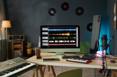 Stüdyoda müzik kaydetmek için mikrofonu ve bilgisayarı olan bir yapımcı işyeri