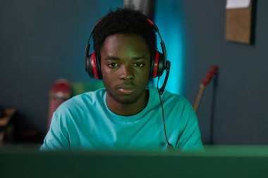 Zoomer in headphones sitting in front of computer monitor and playing virtual reality game clipart