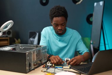 İşine konsantre olan genç bir tamirci, ana kartın bilgisayar parçalarını tamir ediyor.